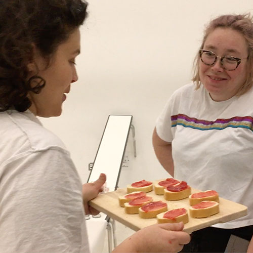 Performer Yifat Shir-Moskovitz is handing out pieces of bread with the freshly made jam to the audience